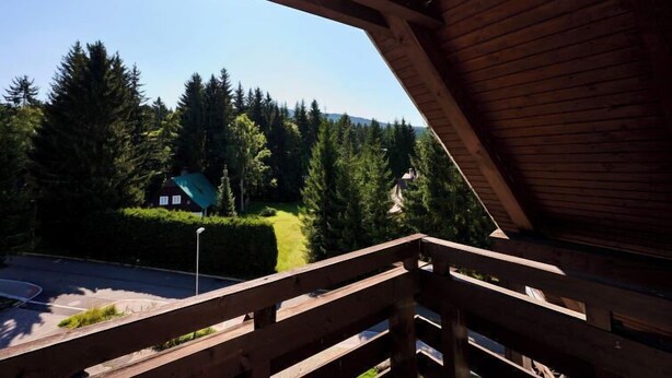 A wooden balcony with a view of a forested area and a road. - Harrachov 497 by Interhome (Harrachov)