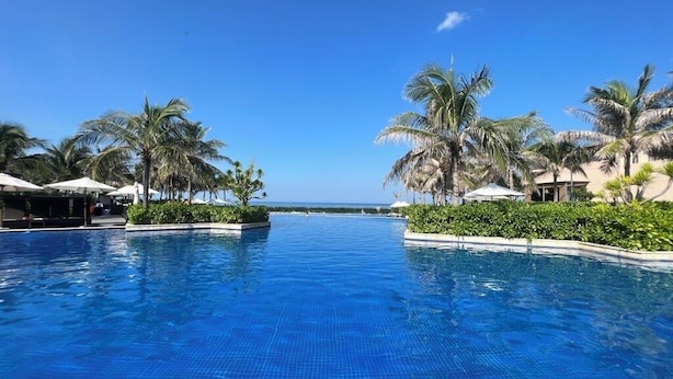 A swimming pool with palm trees and a clear sky. - VILLA PHONGLIEM (Cam Lam)