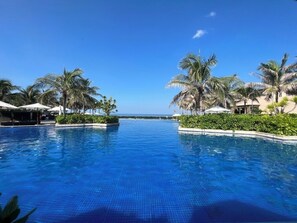 Una piscina al aire libre, sombrillas, sillones reclinables de piscina