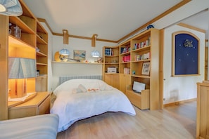 A bedroom with a bed, wooden shelves, a desk, and a bookshelf.