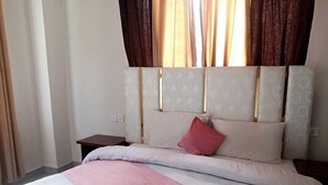 A hotel room with a bed, a nightstand, and a window with curtains.