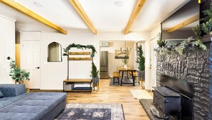 Een woonkamer met een bank, een open haard, een eethoek en een keuken op de achtergrond.