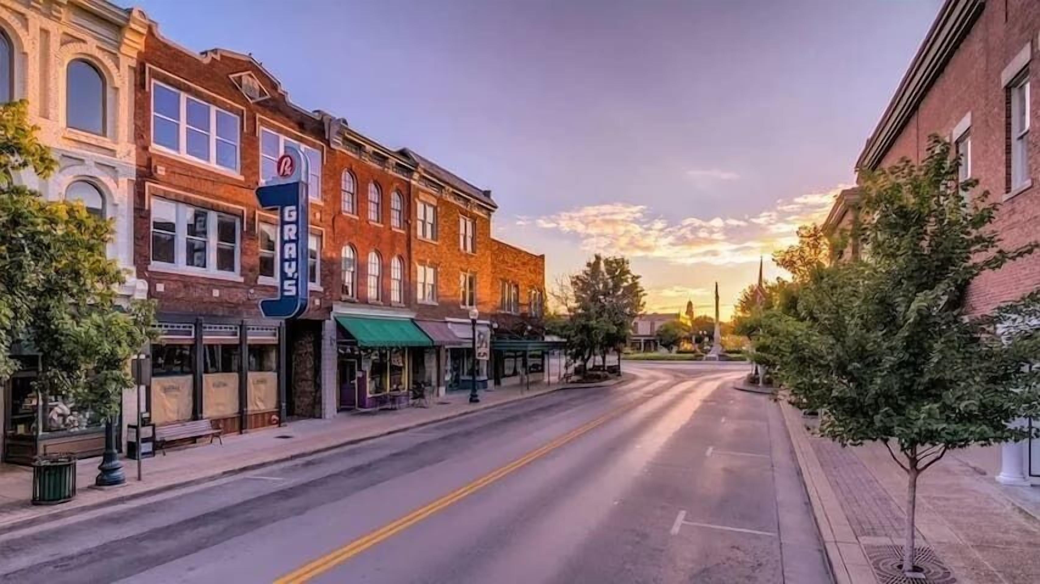 Une rue tranquille bordée de bâtiments historiques, un ciel dégagé et un coucher de soleil.