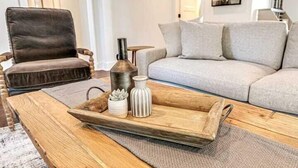 Un salon avec un fauteuil en cuir marron, un canapé gris et une table basse en bois sur laquelle se trouve un plateau avec un vase et une plante succulente.