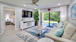 Een moderne woonkamer met een plafondventilator, een flatscreen televisie, een bank en een salontafel.
