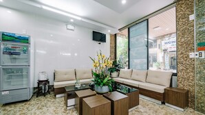 A modern reception area with a sofa, coffee table, and a Sanaky refrigerator. - Phuong Dong Hotel (Hai Phong)