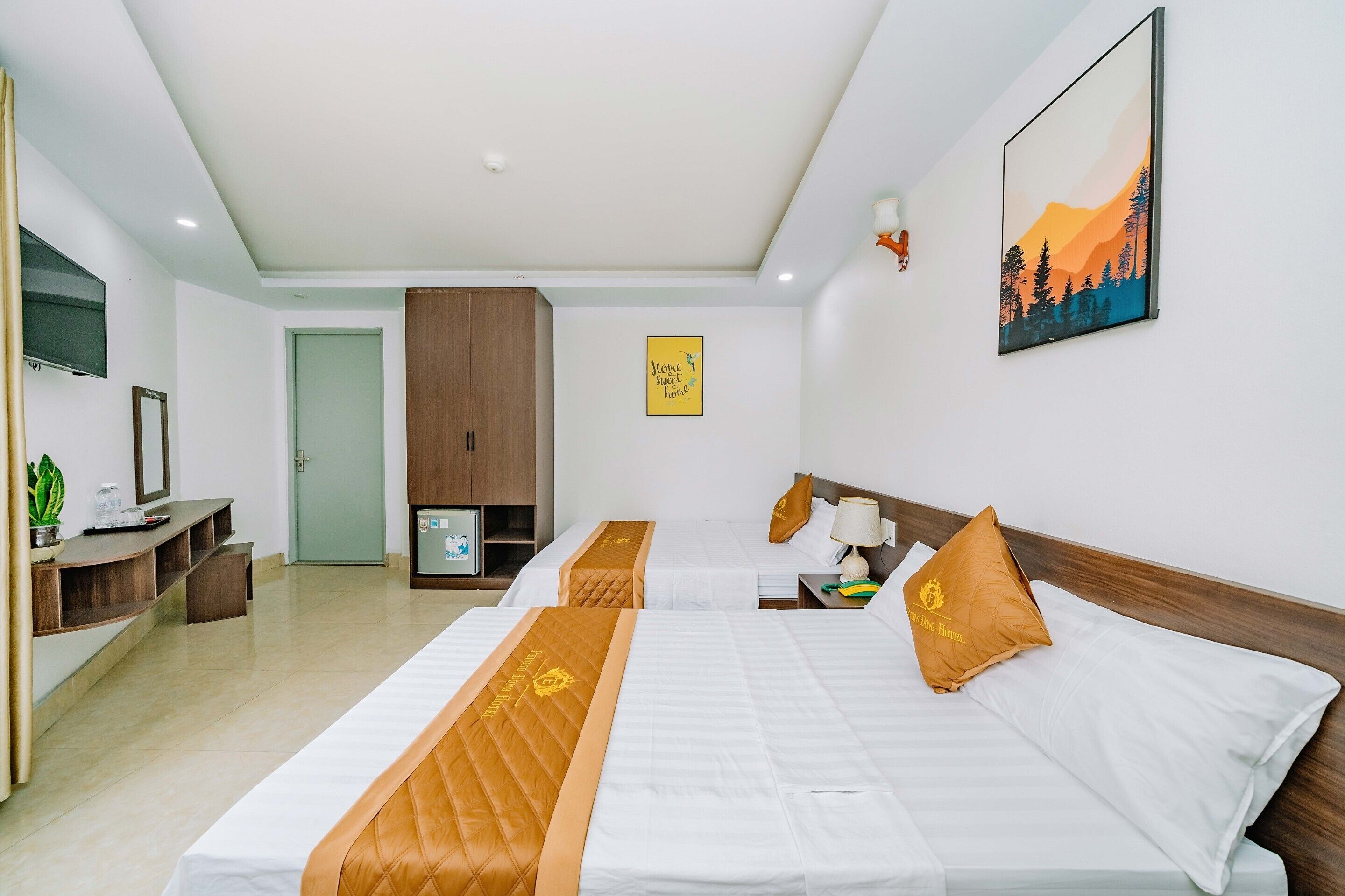 A hotel room with two beds, a TV, a desk, and a door.