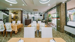 A hotel dining area with round tables, white chairs, and a reception desk. - Phuong Dong Hotel (Hai Phong)