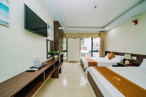 A hotel room with two beds, a TV, a desk, and a window with curtains. - Phuong Dong Hotel (Hai Phong)
