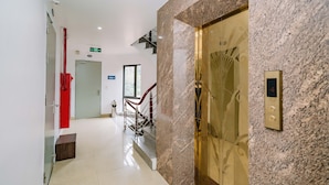 A modern hotel lobby with a marble reception desk, a staircase, and an elevator. - Phuong Dong Hotel (Hai Phong)