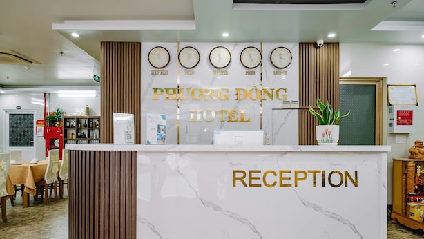 A reception area with a marble counter, clocks displaying time in New York, Tokyo, Vietnam, Paris, and London, and a sign reading "PHUONG DONG HOTEL RECEPTION". - Phuong Dong Hotel (Hai Phong)