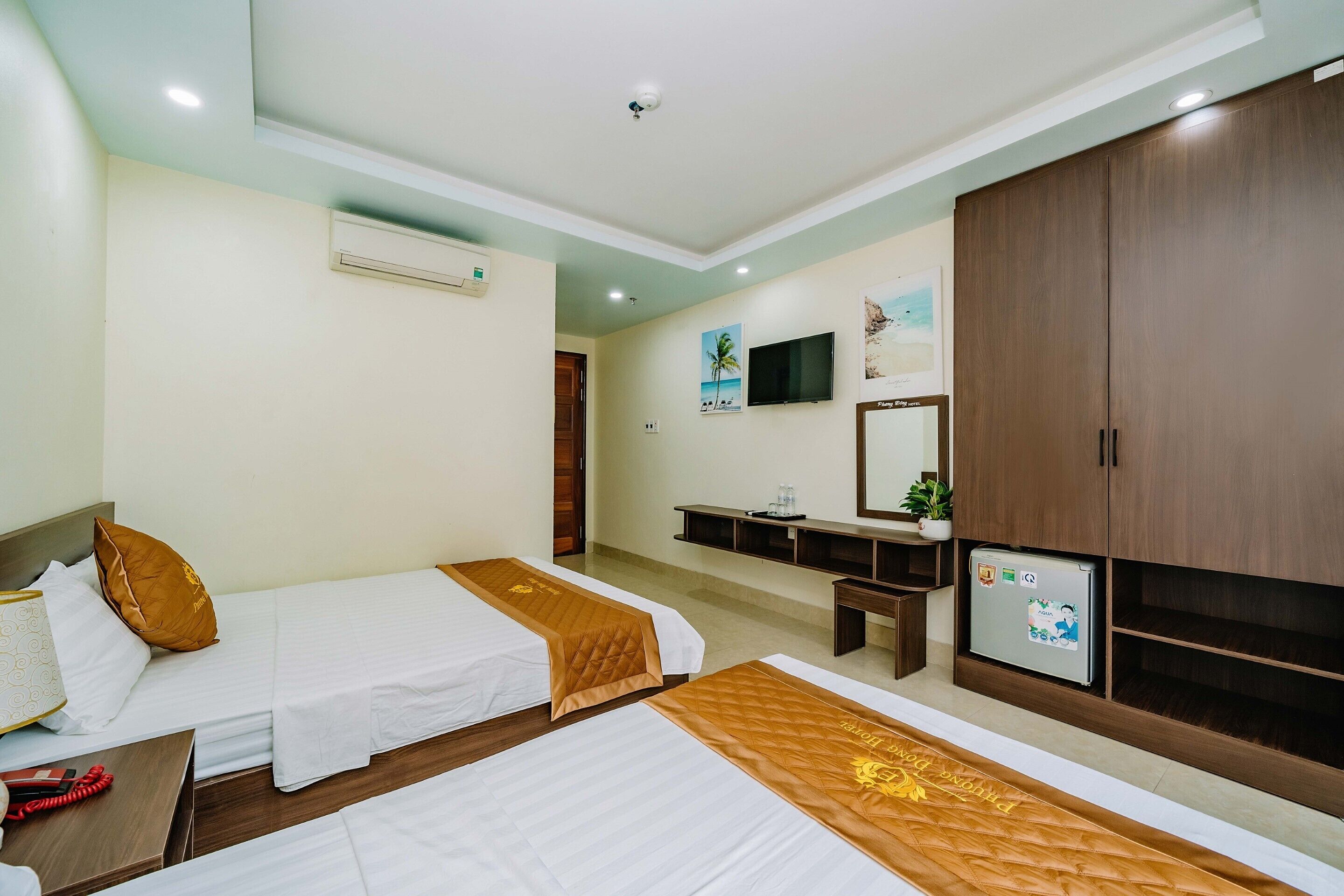 Habitación de hotel con dos camas, un televisor, un armario y un escritorio con silla.