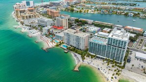 An aerial view of a coastal city with a marina, hotels, and a beach.
