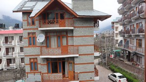 Un edificio de varios pisos con balcones, una antena parabólica y un automóvil estacionado.