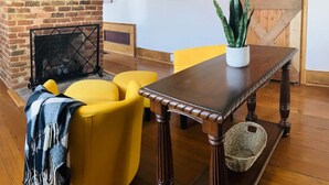 A room with a brick fireplace, yellow chairs, a wooden table, and a potted plant. - Farm, Fireplaces, Kayaks, River & Mountain Views (Luray)
