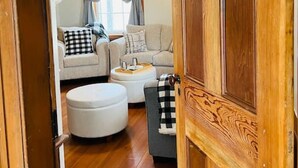 A wooden door leading into a living room with a sofa, ottoman, and a small table. - Farm, Fireplaces, Kayaks, River & Mountain Views (Luray)