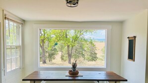 A room with a large window, a wooden bench, and a small table with a plant. - Farm, Fireplaces, Kayaks, River & Mountain Views (Luray)