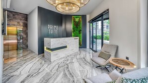 A modern reception area with a marble reception desk, a green vertical garden, and a seating area with a sofa and armchair. - Prime Suite Alanya (Alanya)