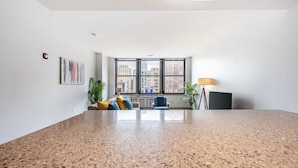A modern living room with a large window, a sofa, a coffee table, and a lamp.