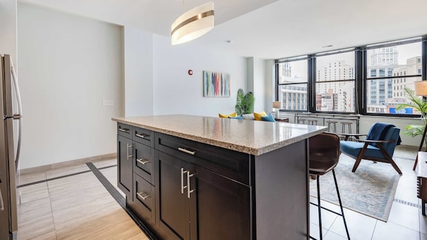 A modern kitchen with dark cabinetry, a granite countertop, and a large window offering a city view.