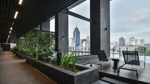 Een modern terras op het dak met zitplaatsen en plantenbakken, met uitzicht op een stadshorizon.
