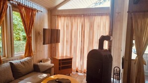 A cozy living room with a sofa, a small table, a TV, and a wood stove. - Extertal-ferienpark - Komfort-ferienhaus Wandern Mountainbike Sauna #50 (Extertal)