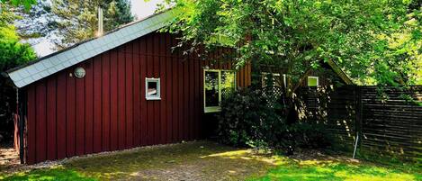 A red barn with a sloped roof, a small window, and a door.