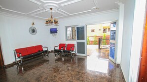 A lobby with a chandelier, a clock, and two red sofas.