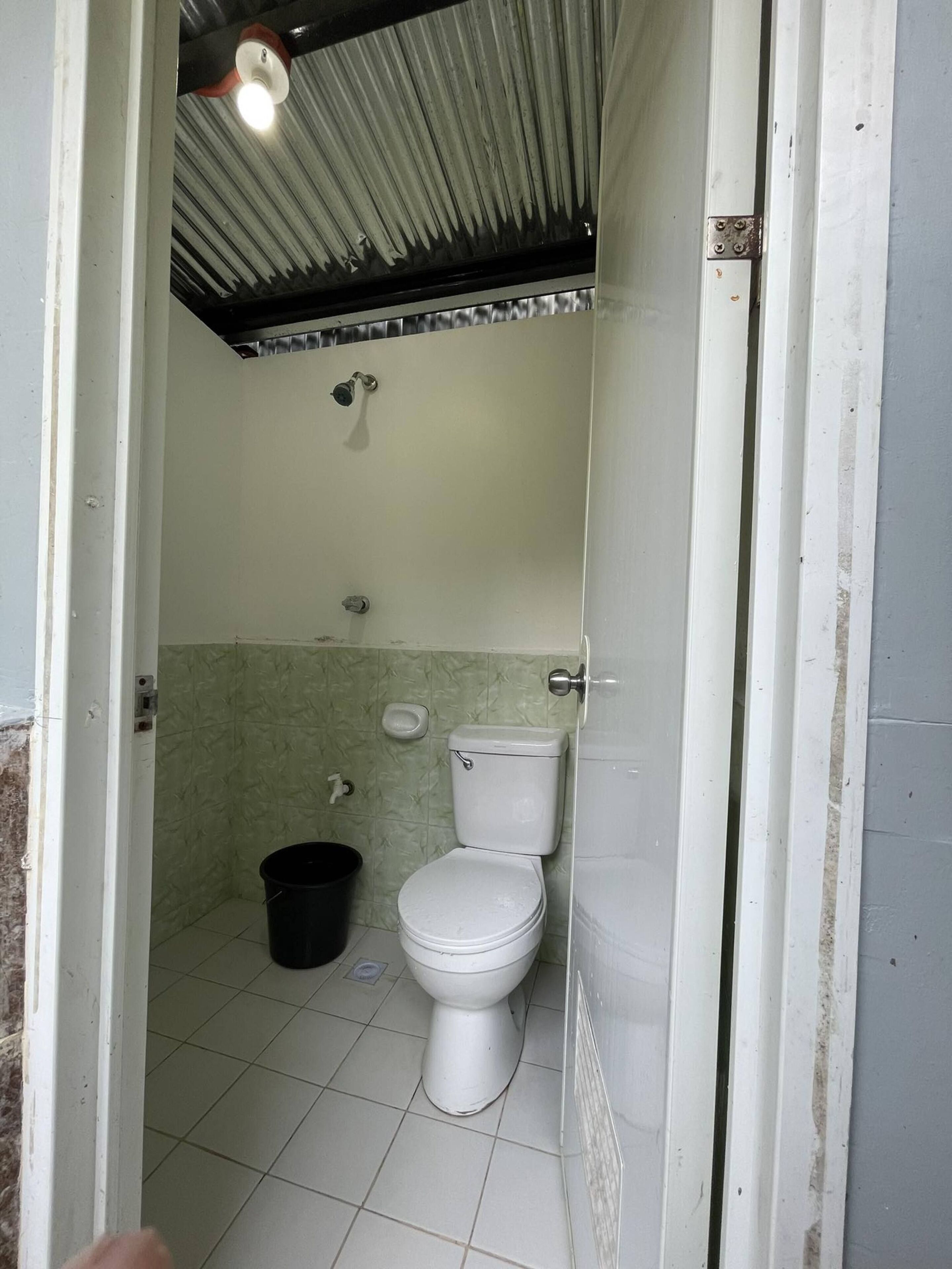 A small, enclosed bathroom with a toilet, a shower, and a sink.