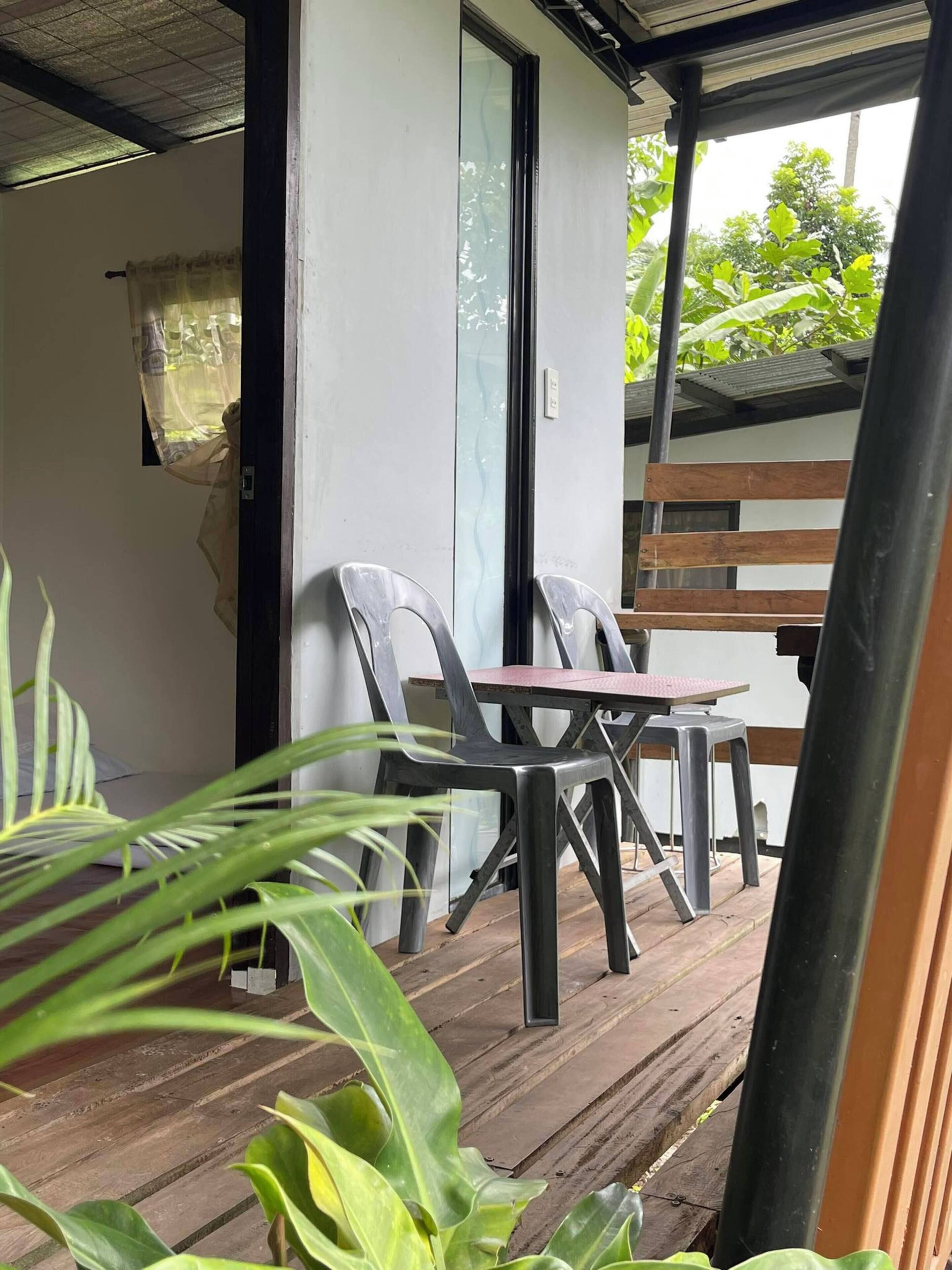 Un espacio de estar al aire libre con techo, una mesa, sillas, una terraza de madera y plantas en macetas.