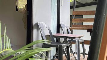 Un espacio de estar al aire libre con techo, una mesa, sillas, una terraza de madera y plantas en macetas.