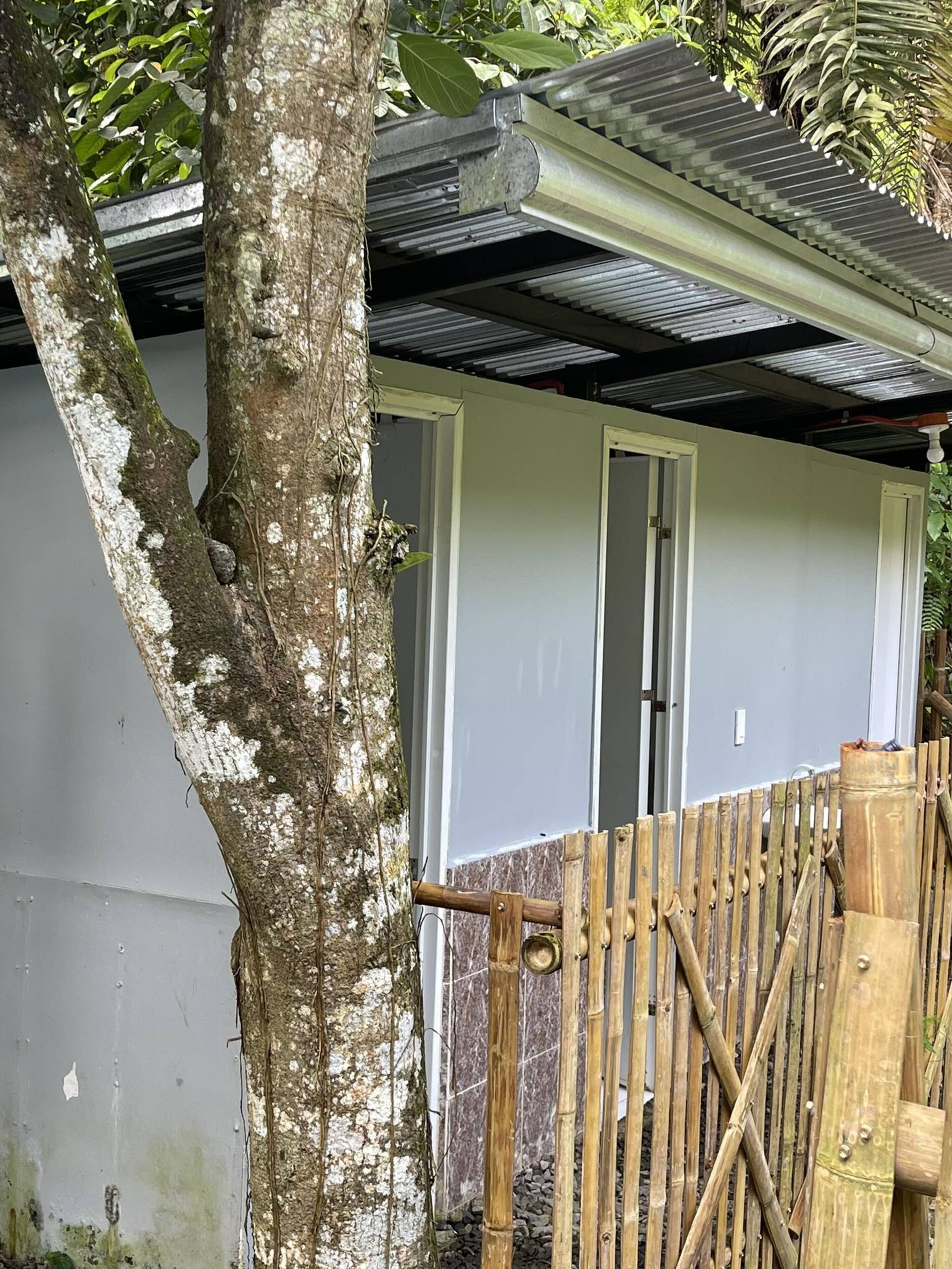 A building with a white exterior, a metal roof, and a bamboo fence.