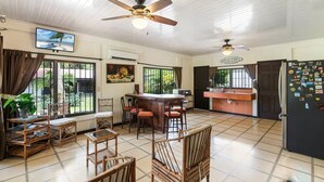 A spacious kitchen with a bar area, wooden furniture, and a ceiling fan. - Stunning Gated Property with a Lush Garden, Wrap-Around Terrace & Private Pool (Potrero)