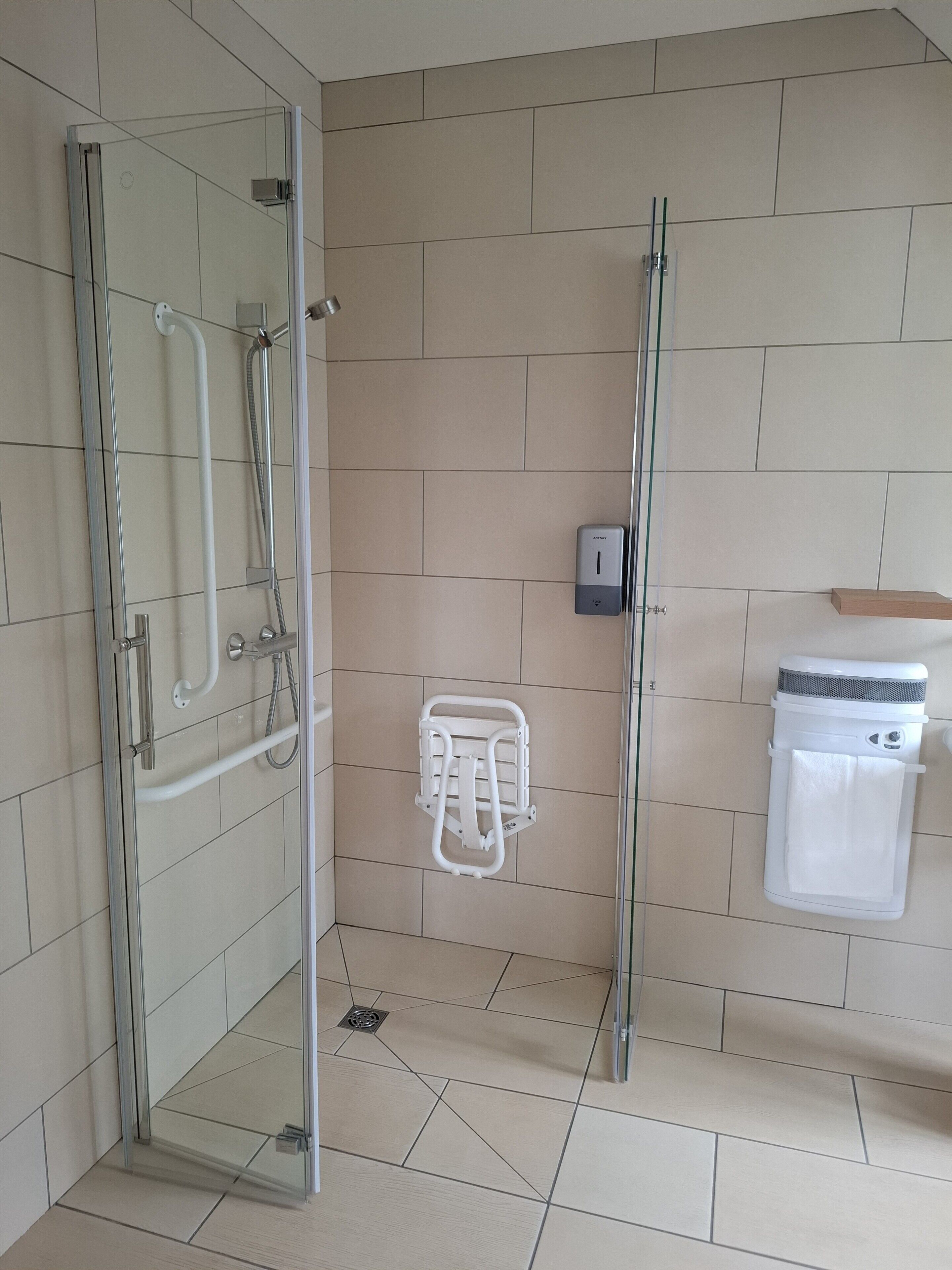 Een moderne badkamer met een douchecabine van glas, een handdroger en een handdoekrek.