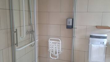 Een moderne badkamer met een douchecabine van glas, een handdroger en een handdoekrek.