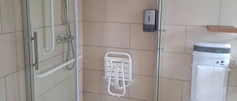 Un baño moderno con cabina de ducha de vidrio, un secador de manos y un perchero para toallas.
