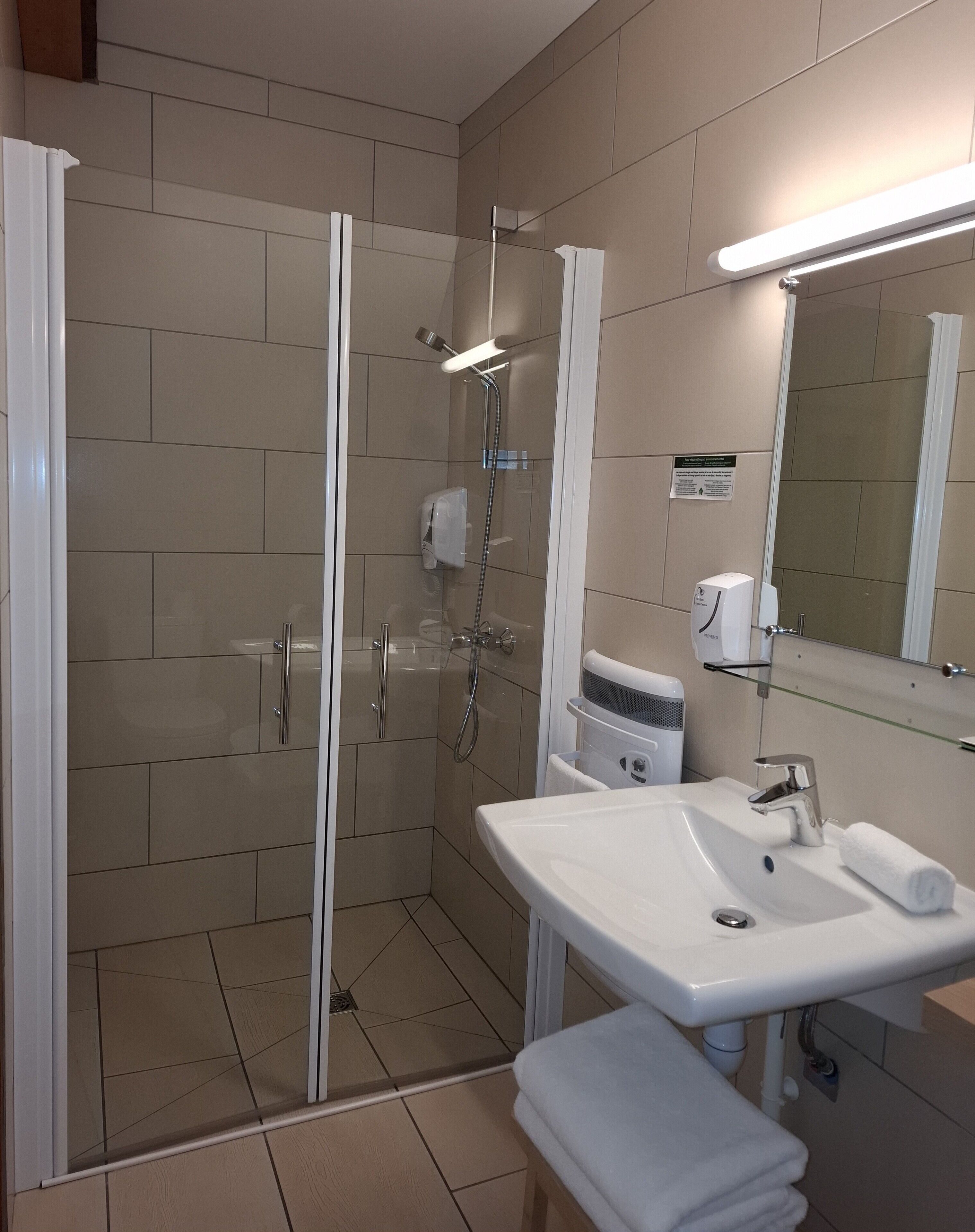 A modern bathroom with a glass-enclosed shower, a white sink, and a mirror above it.