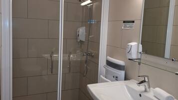 A modern bathroom with a glass-enclosed shower, a white sink, and a mirror above it.