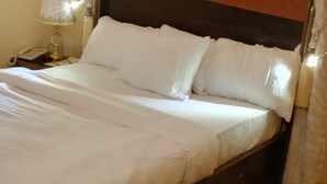 A neatly made bed with white linens and a wooden headboard. - NAPTIN EXECUTIVE HOTEL AND SUITES  (Jos)