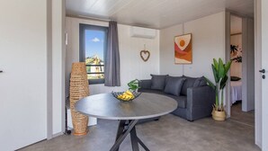 A modern living room with a grey sofa, a round table with a fruit bowl, a large window with a view, and a hanging heart decoration. - Chalet Familial Avec SPA (Saubrigues)