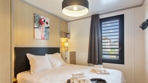 A hotel room with a bed, a headboard, a wall-mounted artwork, a window with curtains, and a bedside lamp. - Chalet Familial Avec SPA (Saubrigues)