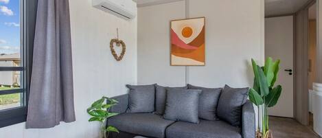 A modern living room with a grey sofa, a small table, and two potted plants.