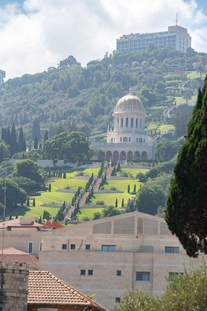 A large, historic building with a dome and arched windows, surrounded by lush greenery and a well-maintained garden.