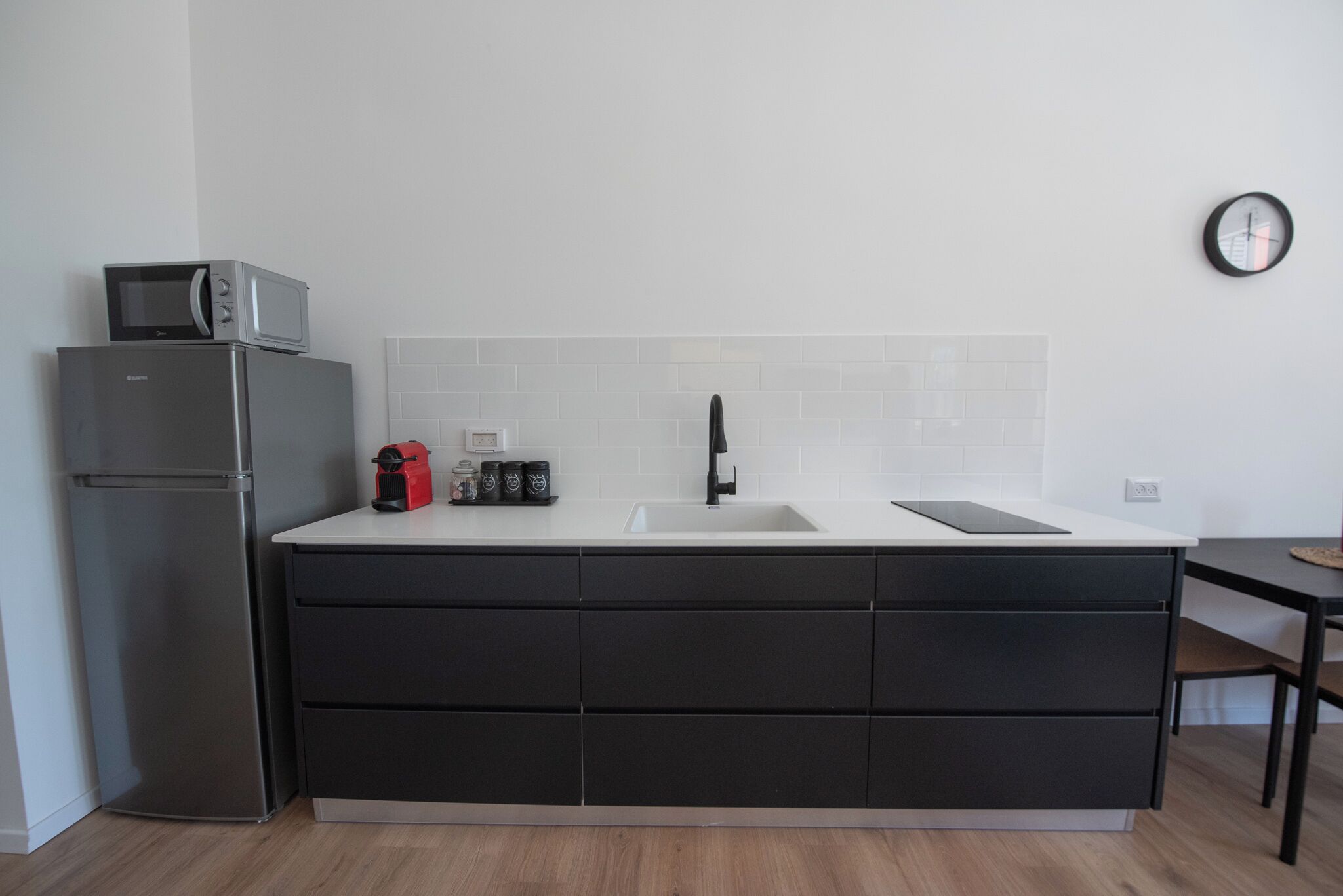 A modern kitchen with a built-in microwave, stainless steel refrigerator, and a black countertop.