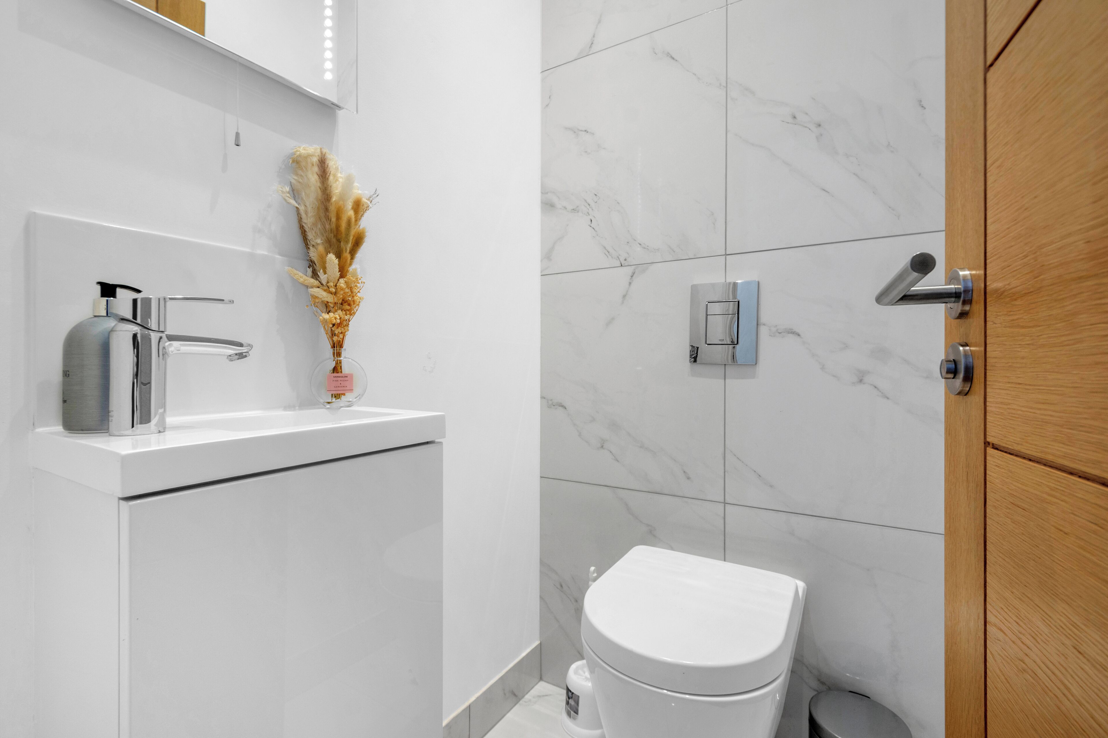 A modern bathroom with a white sink, a toilet, and a shower area.