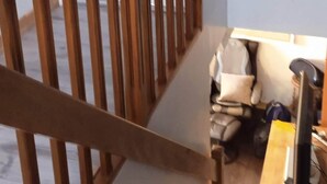 Uma escada de madeira com corrimão que leva a uma área de desembarque.