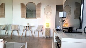 Uma sala de estar moderna com um sofá, uma mesinha e uma TV. Há sonhadores pendurados na parede e um abajur sobre a mesa.