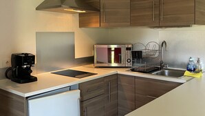 Eine moderne Küche mit Holzausbau, einer integrierten Mikrowelle, einer Kaffeemaschine und einem Spülbecken.