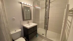 Ein Badezimmer mit Toilette, Waschbecken, Spiegel und Duschkabine.