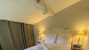 Ein ordentlich bezogenes Bett mit weißer Decke und Kissen, zwei Nachttischlampen und ein Holzboden.
